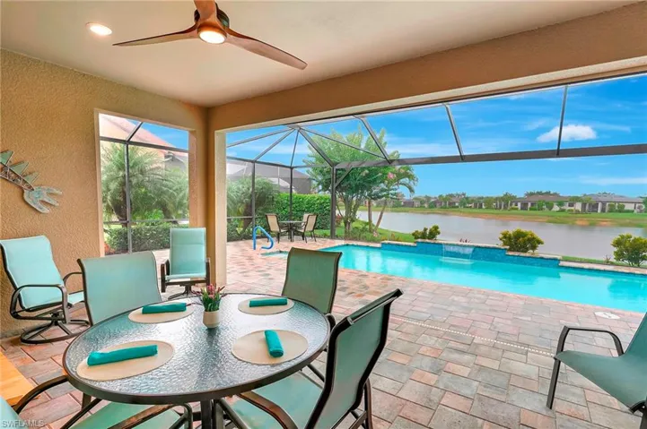 Outdoor pool featuring a patio area, glass enclosure, a ceiling fan, a water view, and a sunroom