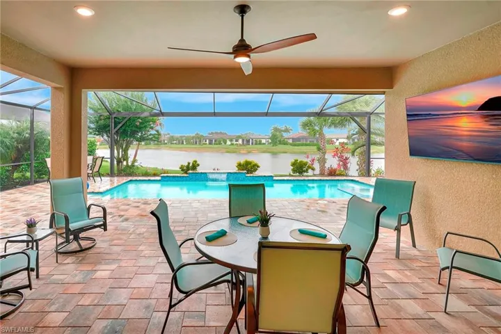 Swimming pool featuring a sunroom, a patio, a lanai, ceiling fan, and a water view