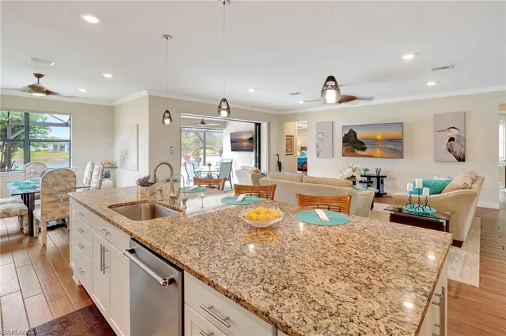 Kitchen with light wood finished floors, open floor plan, an island with sink, ornamental molding, and recessed lighting