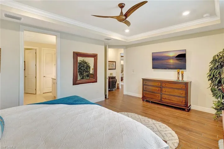 Bedroom with crown molding, light wood-style floors, recessed lighting, a raised ceiling, and ceiling fan
