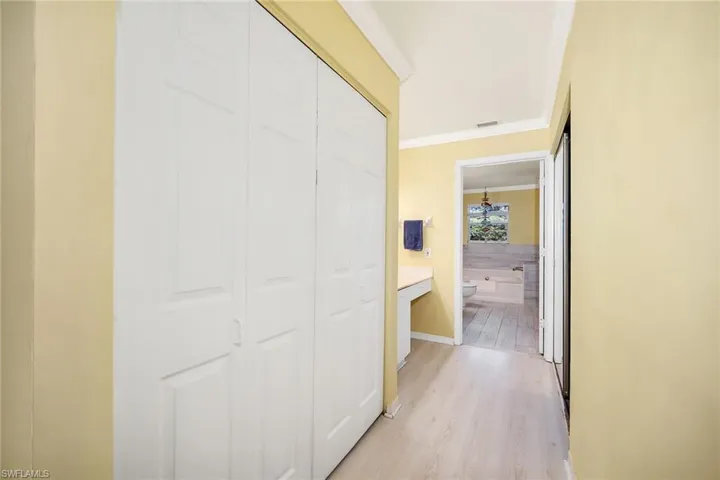 Corridor featuring light wood-type flooring and crown molding