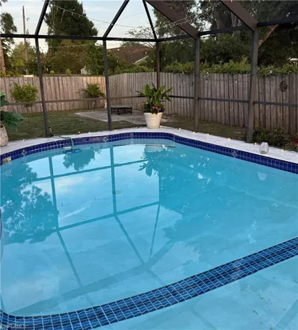 Inviting swimming pool featuring blue mosaic tile accents and a surrounding screened enclosure