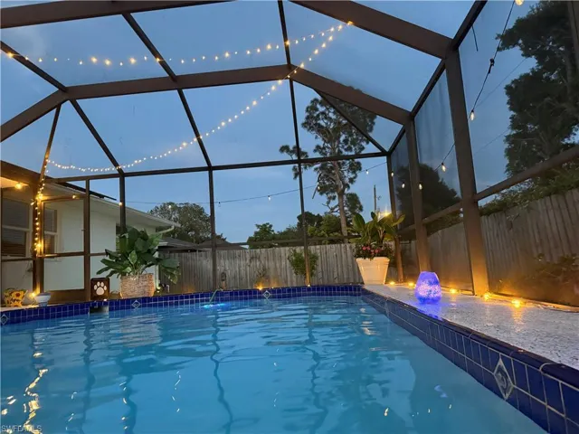 Screened enclosure featuring a swimming pool with blue tile accents and a textured coping