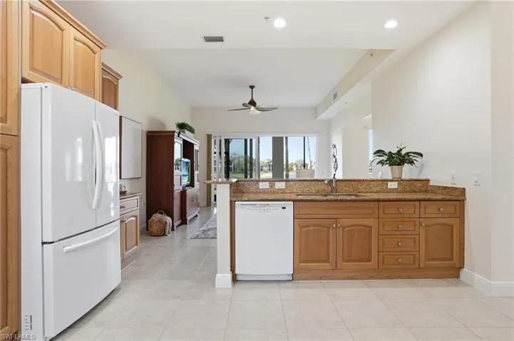 Kitchen featuring white appliances, dark stone counters, a peninsula, wood finish cabinets, and a ceiling fan
