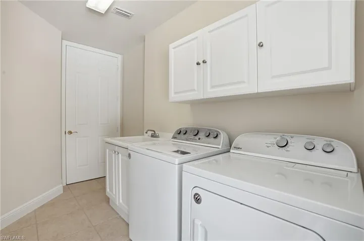 Laundry room featuring cabinet space, light tile patterned floors, and separate washer and dryer