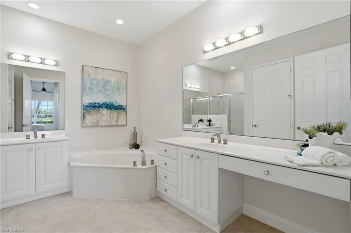 Primary Bathroom with a stall shower, two vanities, a bath, and light tile patterned floors