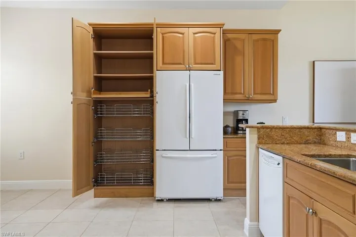 Kitchen with white appliances, light stone countertops, and light tile patterned floors