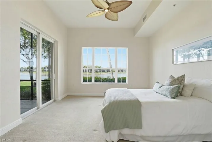 Primary Bedroom with access to outside flooring, a ceiling fan, and a water view