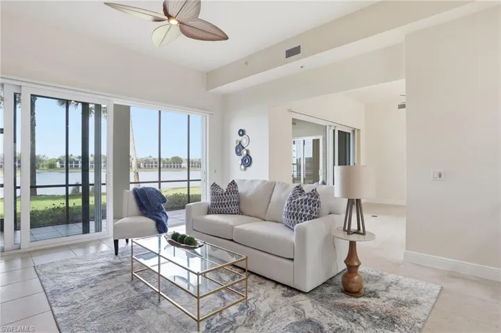 Living room featuring a ceiling fan, a water view, and light tile patterned floors