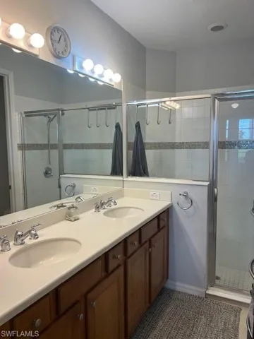 Full bath with double vanity and a shower stall