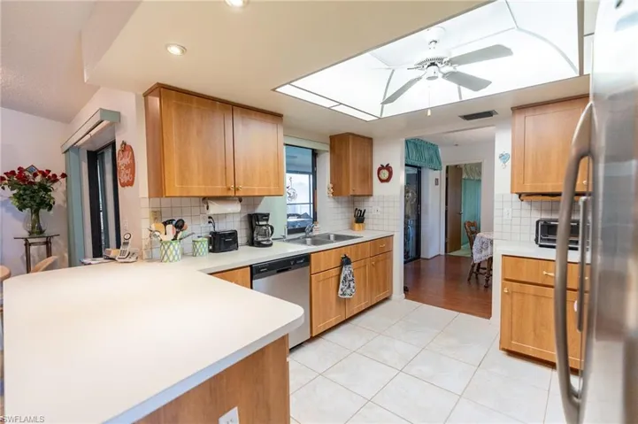 Kitchen pass through to lania and appliances with stainless steel finishes, a ceiling fan, a peninsula, light countertops, and recessed lighting