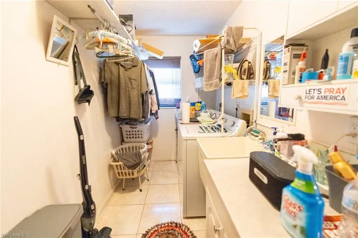 Laundry area with independent washer and dryer,  sink, light tile patterned floors, and a textured ceiling