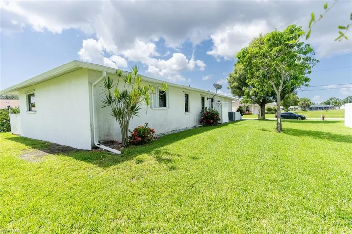 View of side of property featuring a lawn and stucco siding
