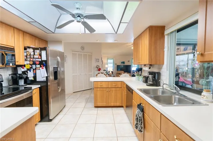Spacious Kitchen with stainless steel appliances, ceiling fan, light tile patterned floors, backsplash, and light countertops