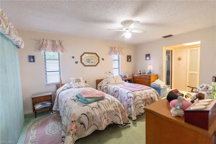 Carpeted Master bedroom featuring multiple windows, a textured ceiling, and ceiling fan