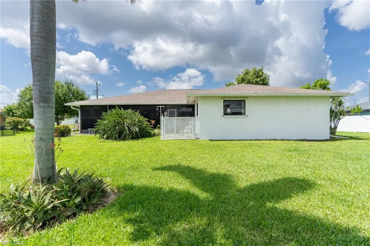 Back of property featuring a sunroom, a yard, and stucco siding