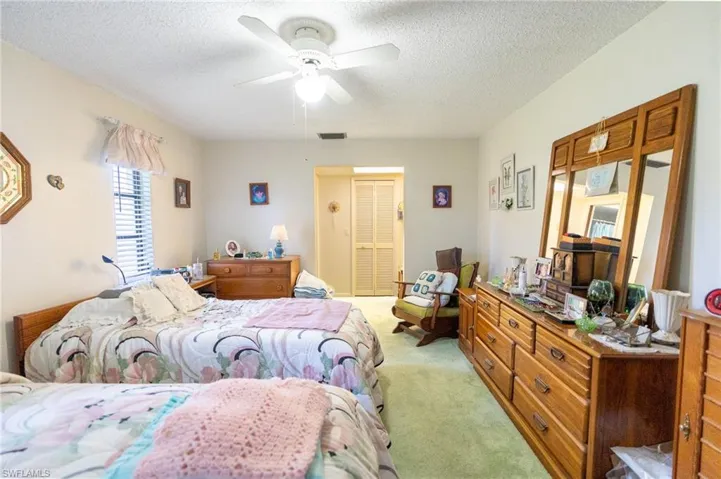 Master Bedroom featuring light carpet, a textured ceiling, ceiling fan, and a closet