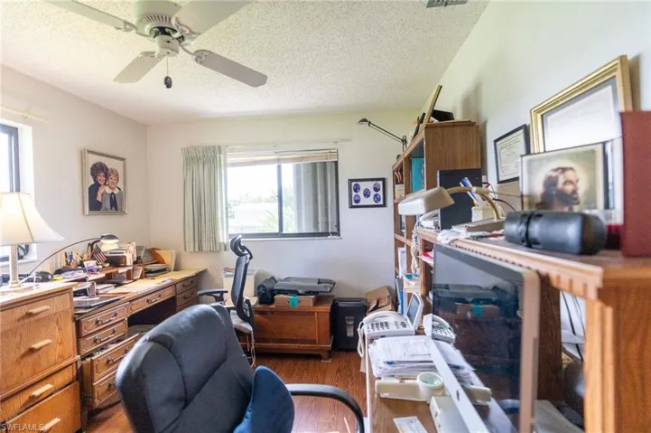 Bedroom being used as office featuring wood finished floors, ceiling fan, closet and a textured ceiling