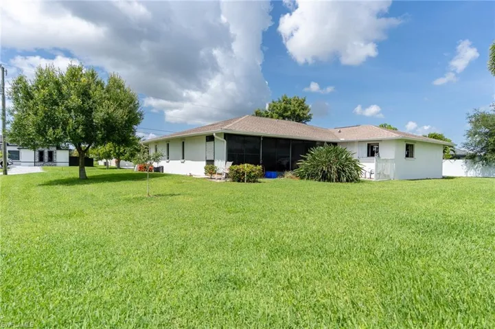 Back of house with a lawn, stucco siding, and a sunroom