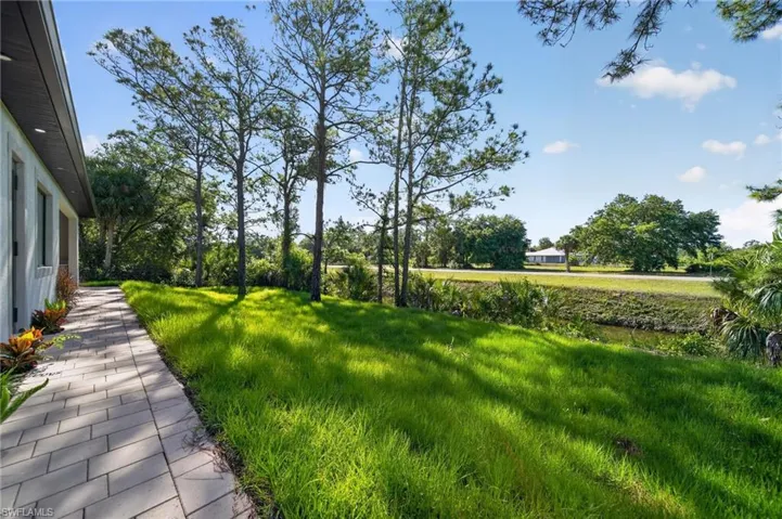 Expansive green lawn bordering a paver walkway, featuring mature trees and established landscaping