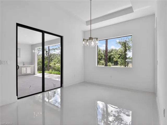 This room features bright white walls, polished floors, and a modern chandelier
