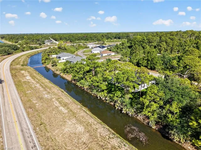 Aerial perspective showcasing a residential area bordered by a waterway and a paved road
