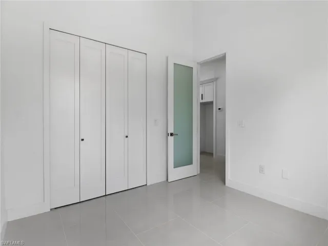 This room features light gray tiled flooring, crisp white walls, and white bi-fold closet doors