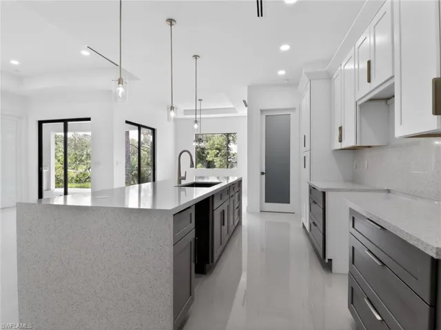 The kitchen features a large island with a light-colored countertop, dark cabinetry, and a sink with a gooseneck faucet