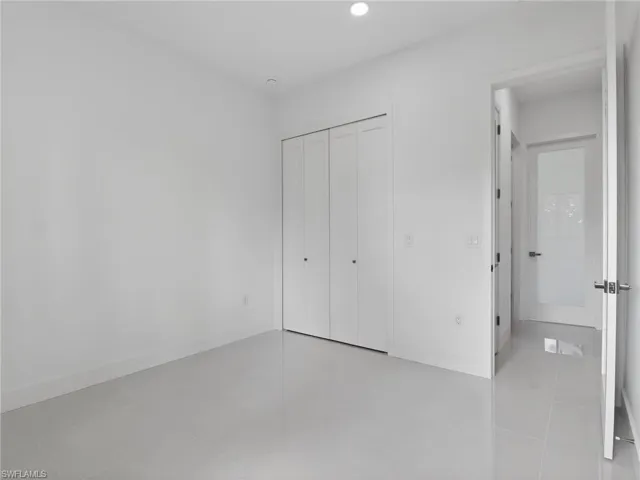 This room features light-colored tile flooring, a closet with bi-fold doors, and recessed lighting
