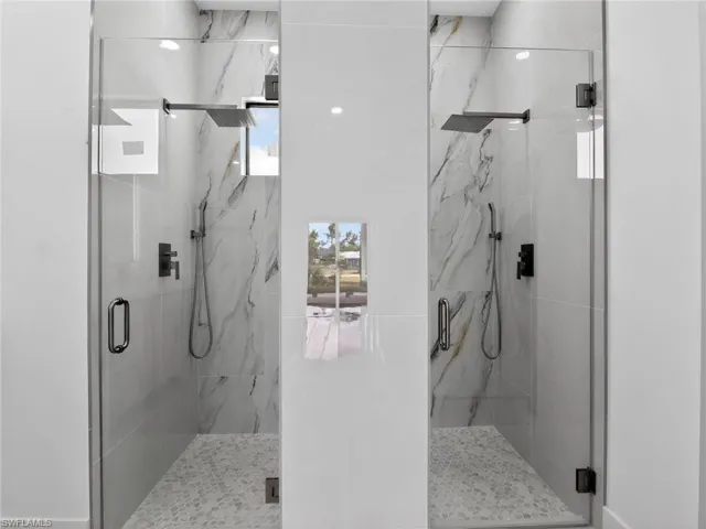Dual walk-in showers featuring white marble-style wall tiling and hexagonal tiled shower floors