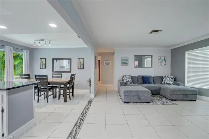Tiled living room with ornamental molding and rail lighting