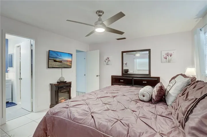 Bedroom with tile flooring, connected bathroom, and ceiling fan