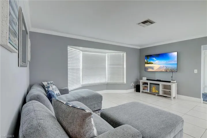 Living room with crown molding and light tile flooring