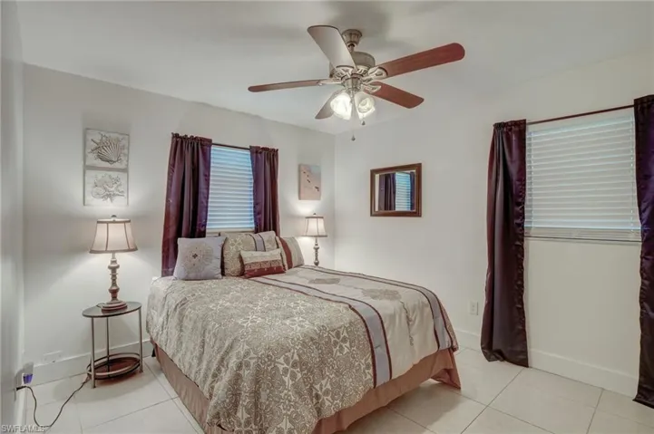 Bedroom featuring multiple windows, ceiling fan, and light tile floors