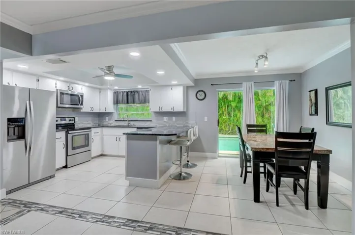 Kitchen with ceiling fan, kitchen peninsula, stainless steel appliances, sink, and white cabinets