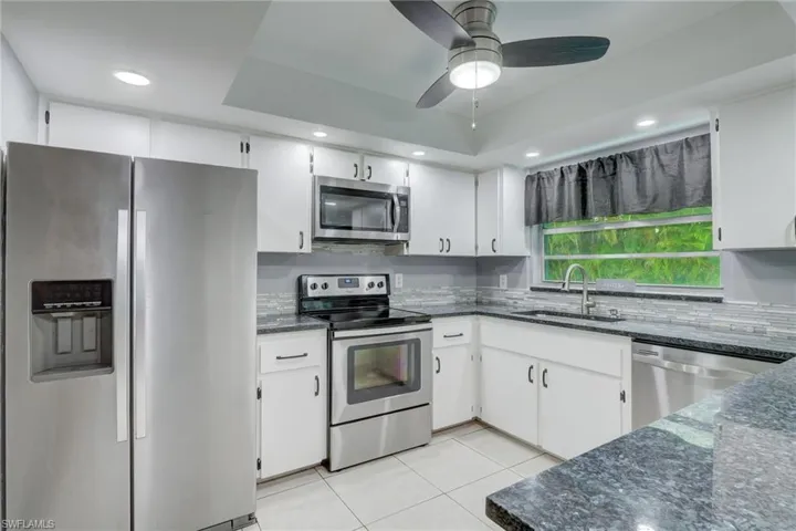Kitchen featuring sink, white cabinets, ceiling fan, and stainless steel appliances