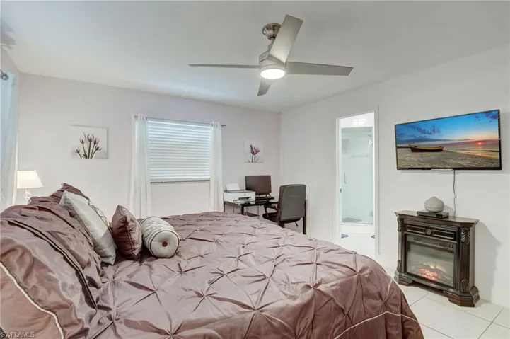 Bedroom with a spacious closet, ceiling fan, and light tile floors