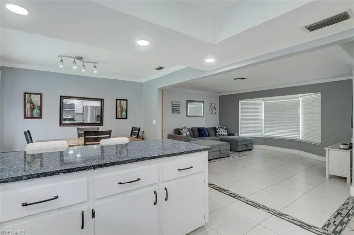 Kitchen featuring white cabinets, dark stone countertops, stainless steel fridge with ice dispenser, and light tile floors