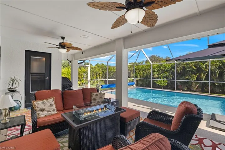 View of swimming pool featuring an outdoor living space with a fire pit, ceiling fan, screen enclosure, and a patio area