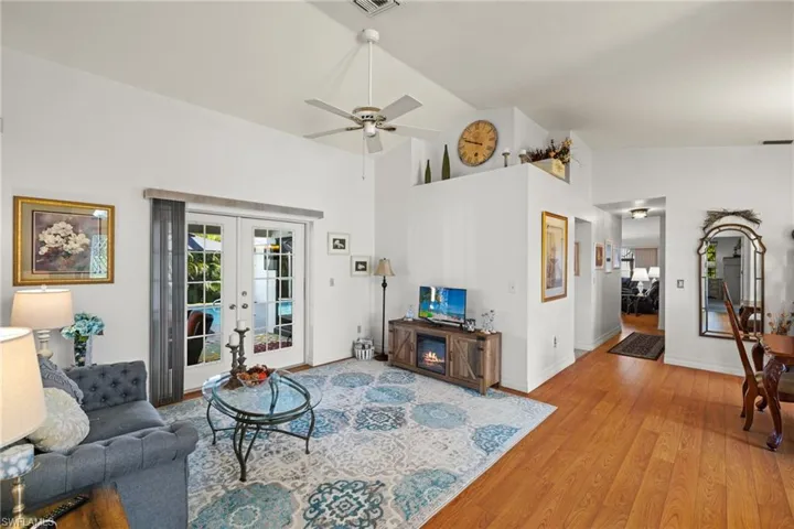 Living room with high vaulted ceiling, french doors, ceiling fan, and hardwood / wood-style flooring