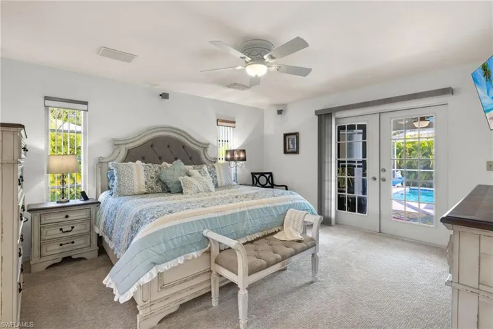 Bedroom featuring light colored carpet, multiple windows, and french doors