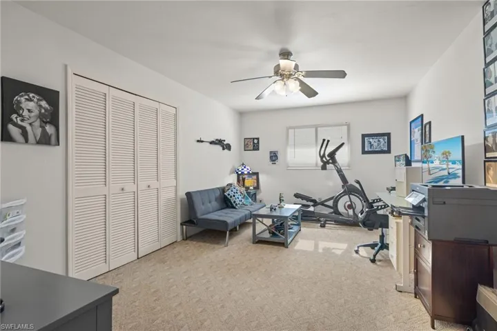 Office area with ceiling fan and light colored carpet