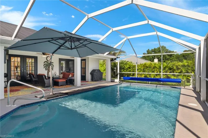 View of swimming pool featuring screen enclosure, french doors, a grill, ceiling fan, and a patio area