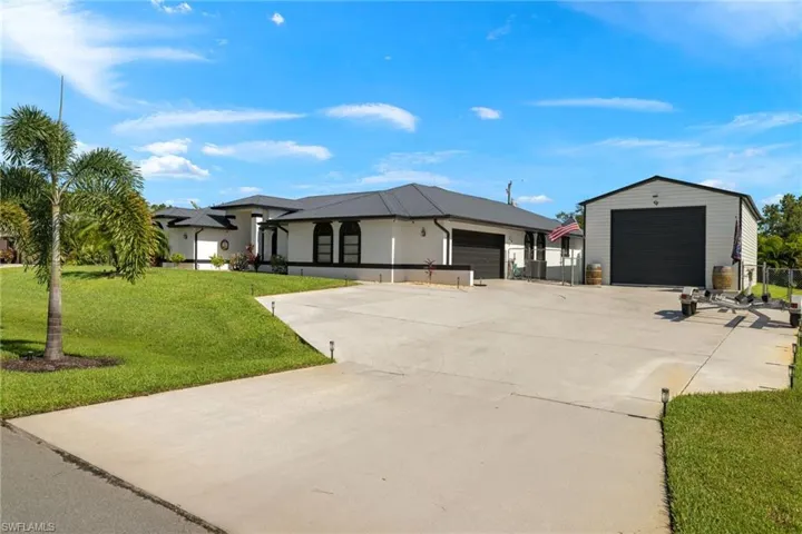 View of front facade with a garage, a front lawn, and an outdoor structure