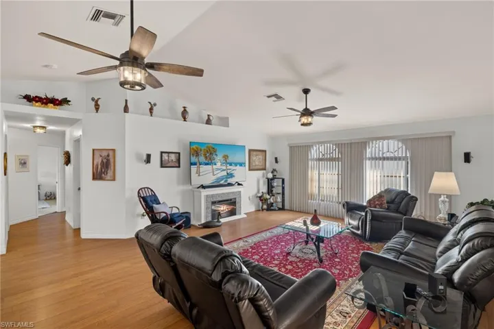 Living room featuring light hardwood / wood-style flooring, lofted ceiling, and two ceiling fans
