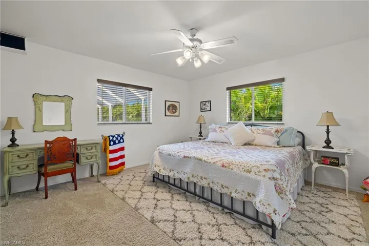 Bedroom featuring multiple windows, light colored carpet, and ceiling fan