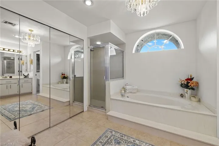 Bathroom with independent shower and bath, a notable chandelier, vanity, and tile patterned flooring