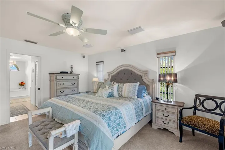 Bedroom featuring ensuite bath, light carpet, and ceiling fan