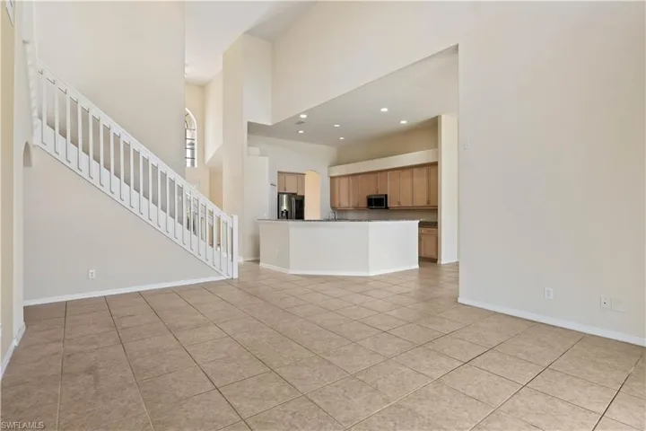 From the staircase landing, enjoy a sweeping view of the open-concept main floor below, with the spacious guest bedroom visible upstairs—highlighting the home’s airy layout and thoughtful design.