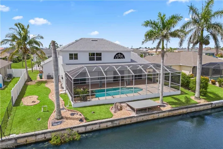 Drone view from the rear of the property displaying the outdoor living space, canal, and surrounding natural beauty—ideal for enjoying Florida’s outdoor lifestyle.